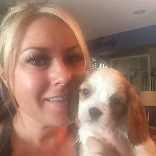 Kelly Holmes smiling with a young Cavalier puppy